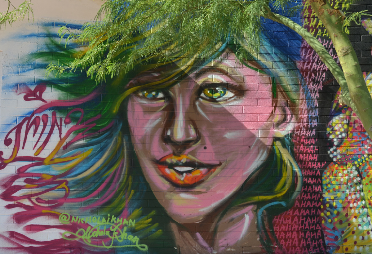 a small tree grows in front of a murl of a large woman's face, the leaves of the tree match the position of woman' hair, by Nicholai Khan, think vegas 