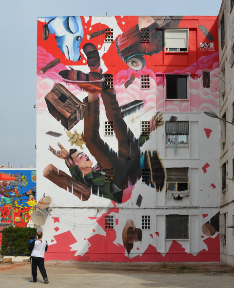a large vertical mural by oldr of a man falling backwards past pink and white clouds. Falling with him is a blue dog, a car, and some logs 