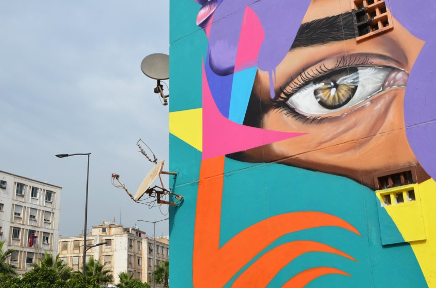 close up of eye in mural with satelite dishes on the building