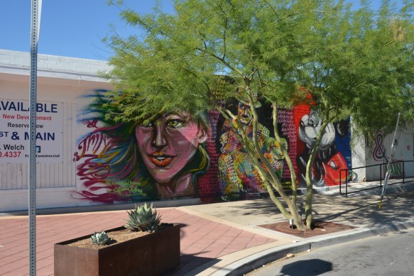 three murals in a row by Nicholai Khan, with #thinkvegas written by them, a woman's face, Charlie Chaplin, and Mickey Mouse 