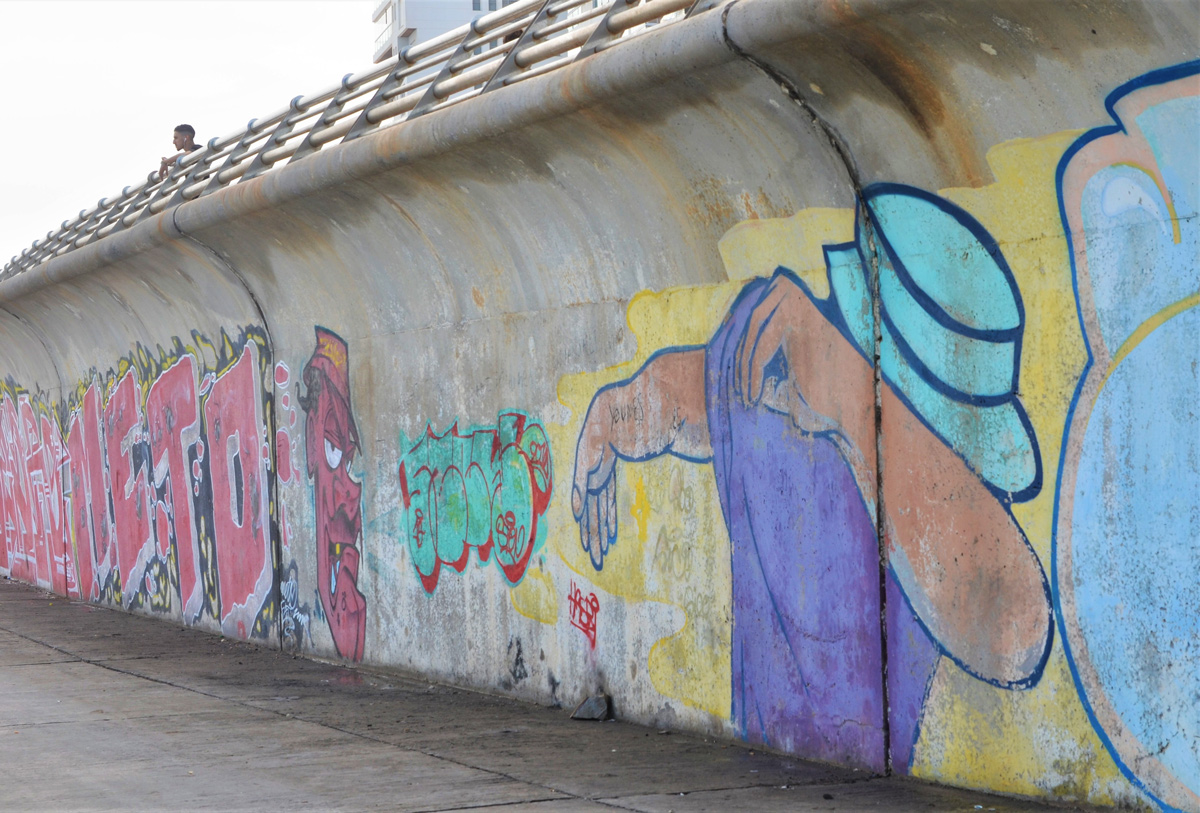 mural with woman in purple shirt and turquoise hat, holding arm in front of her face, mural