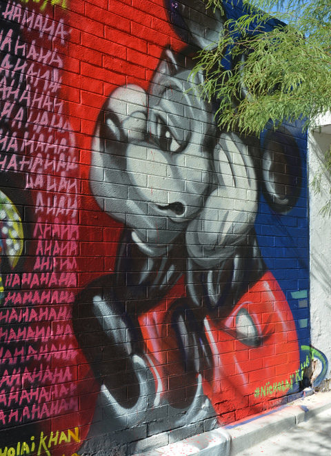 a sad and forlorn MickeyMouse sits with his head resting on his arms, mural