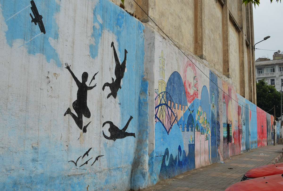 part of a series of murals on a Casablanca wall, three black silhouette figures jumping