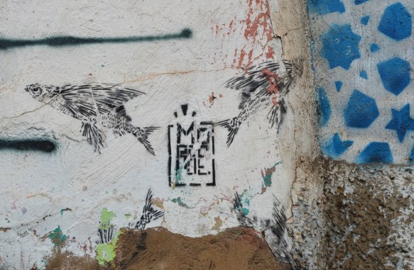 black stencil of four winged fish radiating from the center, tails towards the center 