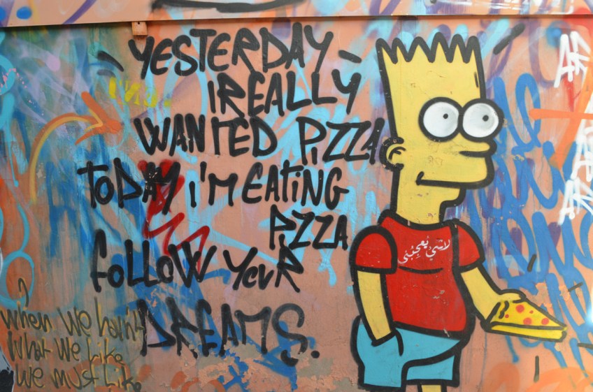 mural with Bart Simpson holding a piece of pizza with words, yesterday I really wanted pizza today I am eating pizza follow your dreams