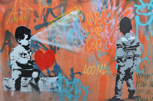 mural by 400 ml, right habd side of mural, bly sitting, large red heart beside him, and rays of light coming from his eyes 