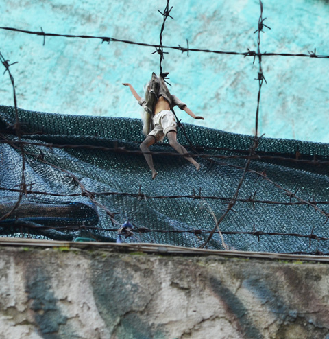 an old Barbie doll caught in a barbed wire fence above a mural