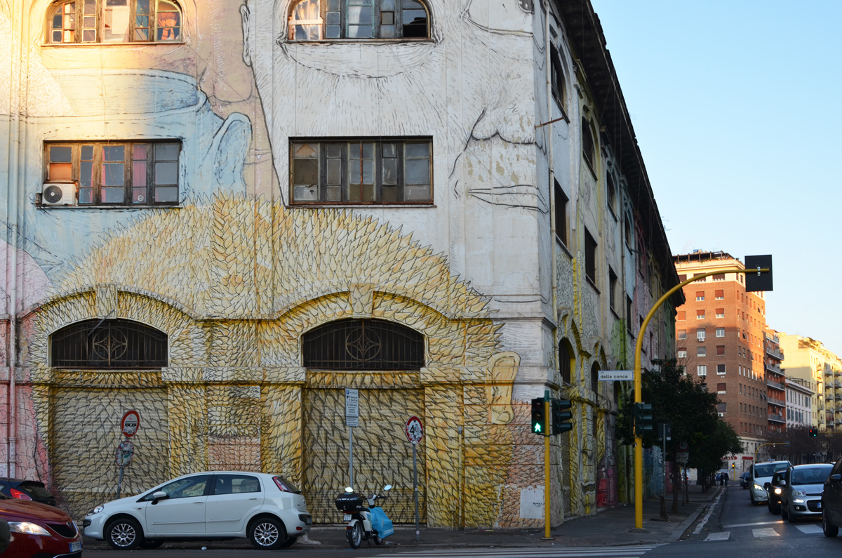 mural in Rome by Blu, on del porto fluviale, of large faces, where the eyes are windows in the buildings, at corner with via della conce