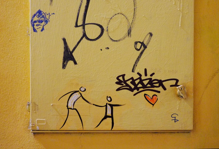 two stick figure people holding hands and reaching for a red heart