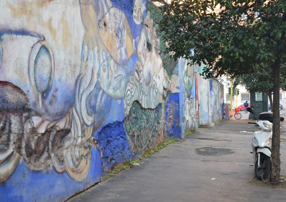 wall with old mural, pieces of wall, breaking off, tree beside woth motorcyle