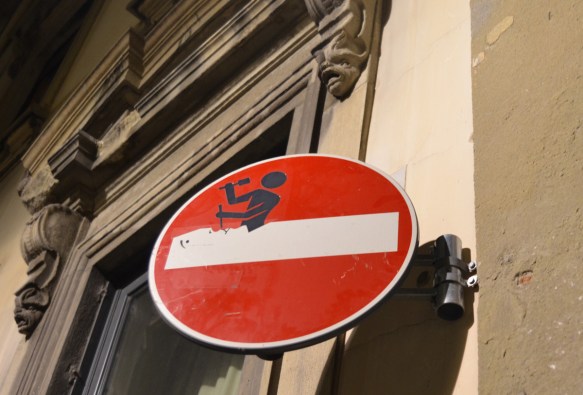 altered red and white no entry sign, graffiti by Clet Abraham, of a man chiseling away the white bar