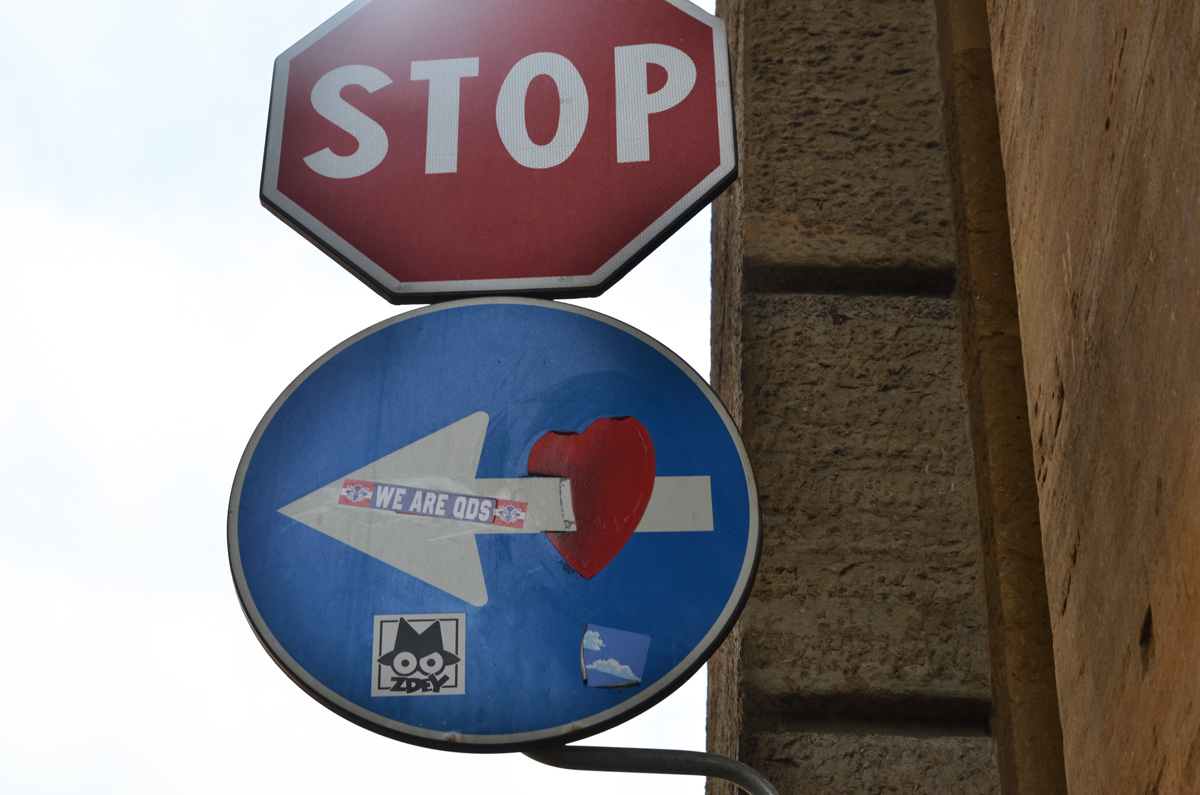 altered blue and white one way sign, the arrow is now piercing a red heart