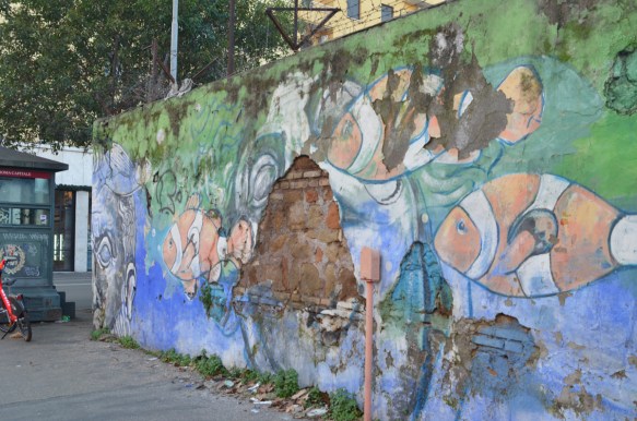 old mural of clown fish and faces on a wall 