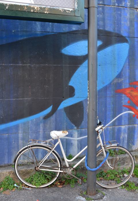 bike parked against a post in front of mural with a whale