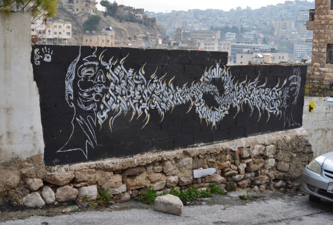 black and white mural of two faces, one at each end, with arabic letters between them 