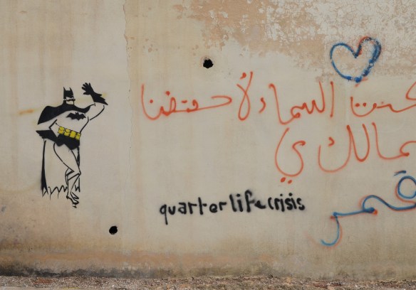 Batman stencils on a wall along with words that someone has written, quarterly life crisis