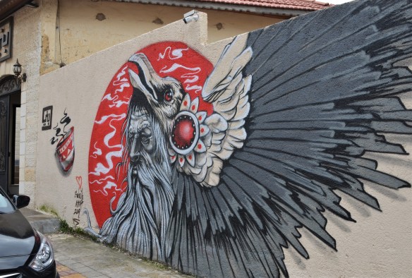 mural by Suhaib Attar of a bird with grey and black wing feathers, on red circle background