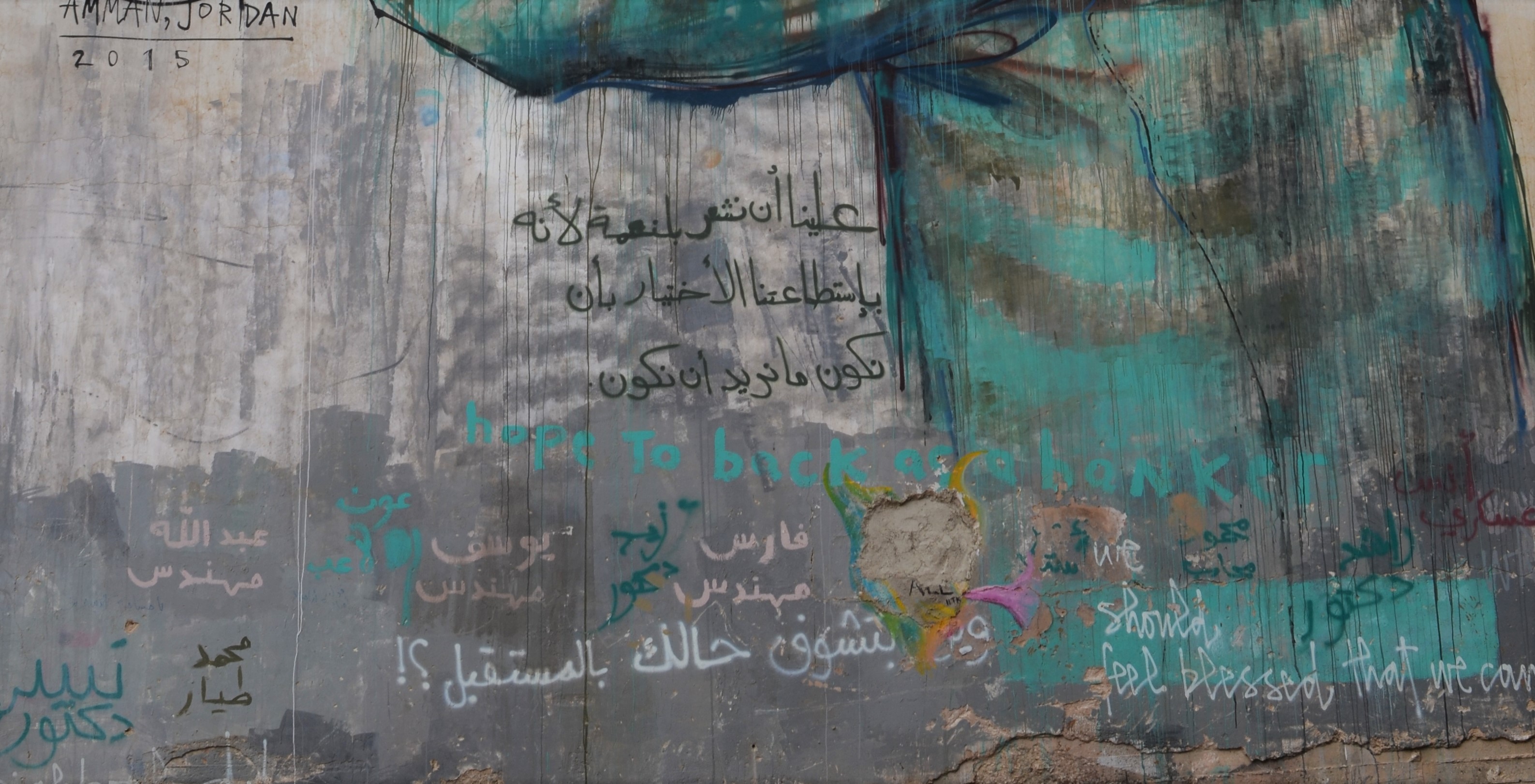details of bottom portion of mural by Herakut, showing Arabic writing that others have added plus the words should feel blessed