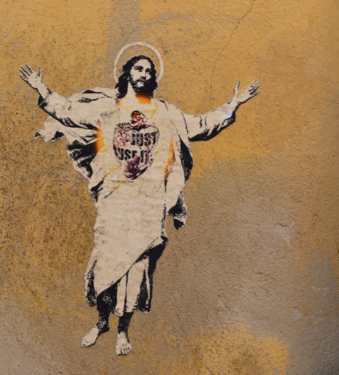 paper paste up of Jesus, white robes, halo, and arms reaching up