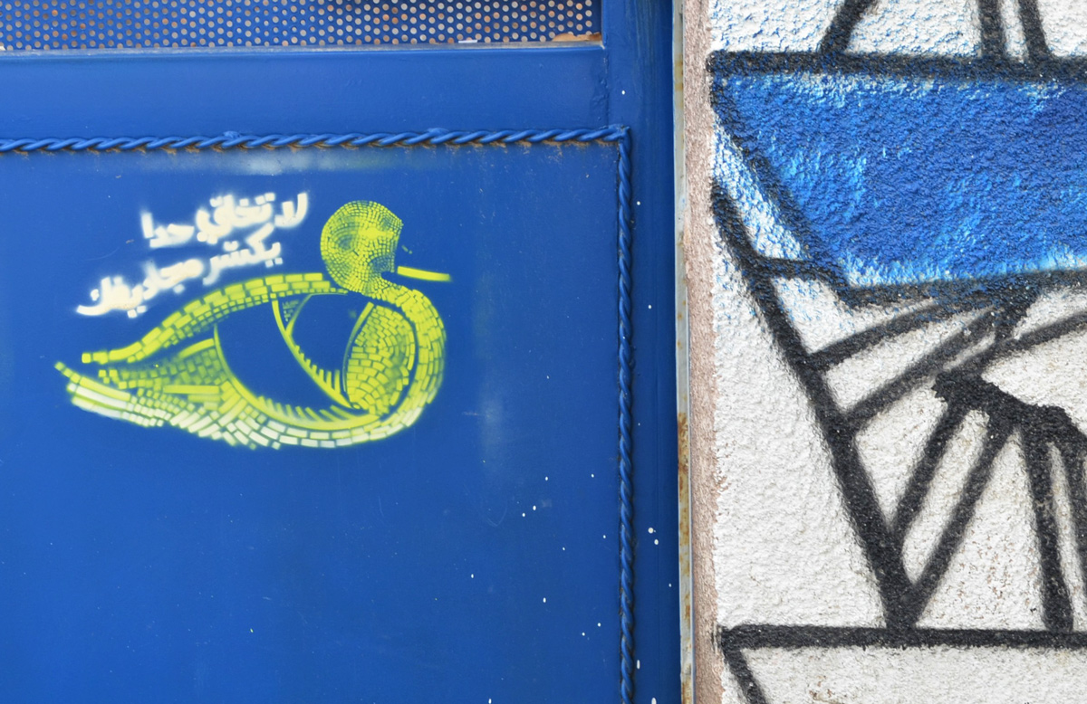 small green stencil of a duck on a blue metal gate