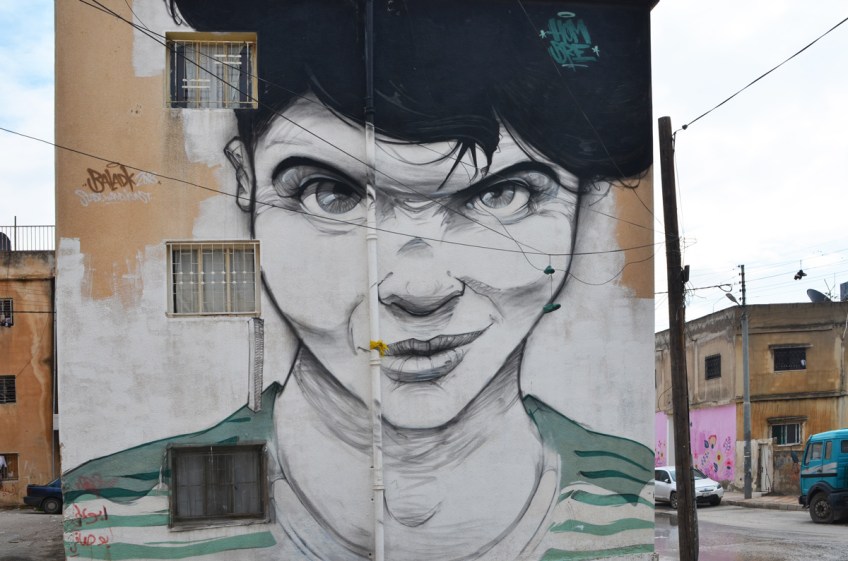 fontal portrait of a person with short black hair and green eyes