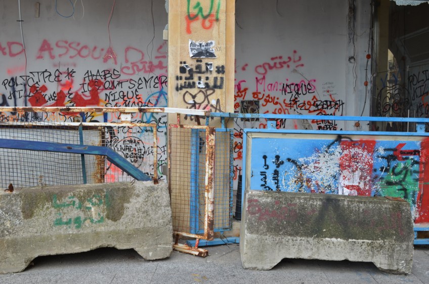 metal and concrete barricades beside a wall covered with tags and graffiti