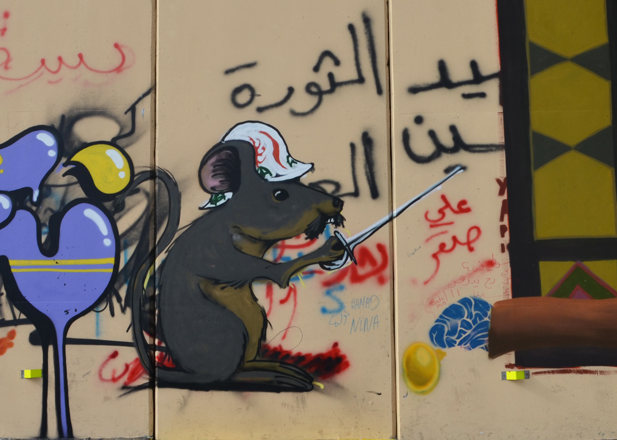 a grey mouse in a hard hat holding a sword, graffiti on a wall 