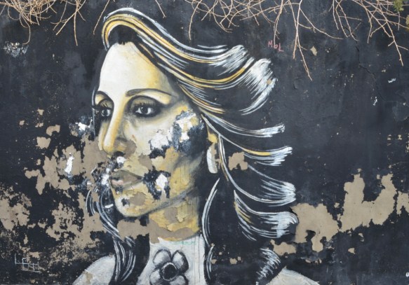 black and white street art painting of a woman on a black background, some of the paint has begun to peel off