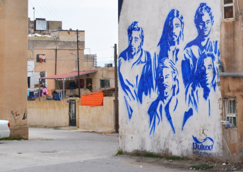 white background, blue paint, mural of a music group with 5 members, part of local vocals