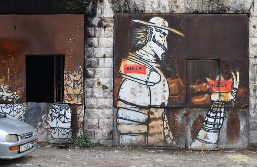 street art painting of a knight in armour holding a crown in his hand, bully written on shoulder of man and on crown