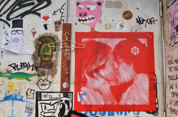 slaps on a wall including a red and white poster of two people kissing 
