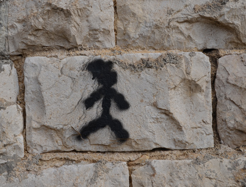 a little black stick figure person painted on a stone wall