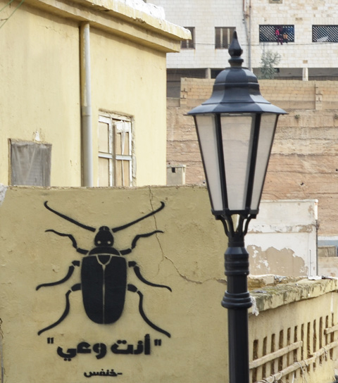 a black beetle graffiti on a yellow wall 