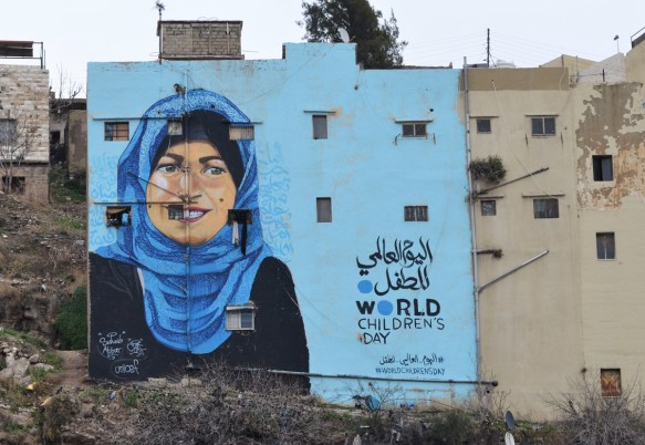 bright blue backkground, on the back of an apartment building, mural, of a woman in blue head scarf, for world children's day, supported by Unicef