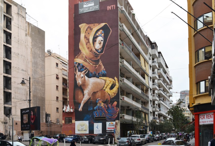 tall Inti mural in Hamras Beirut, of a boy holding onto a goat, boy wearing hooded jacket and a necklace