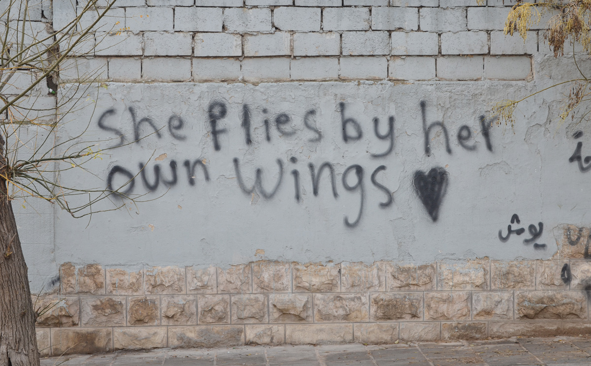 she flies by her own wings, written words painted on a wall, graffiti
