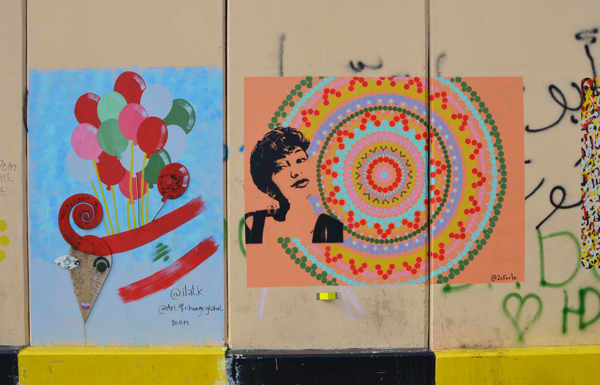 Beirut Revolution Art wall, two pieces, circlar art with woman's face stenciled in black, a painting of balloons and lebanese flag