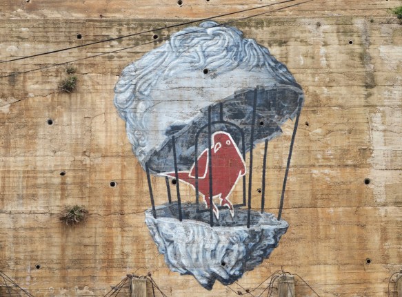 bird in a birdcage that is the shape of a person's head, mural