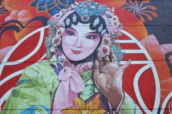 Chinese woman in mural, pink bow at her neck, flowers in her bonnet 