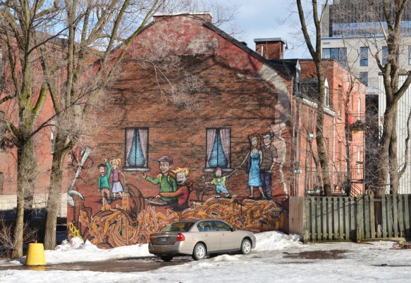 on the end of a brown brick building, a mural of people walking on large noodles that are coming out of a very large ladle 