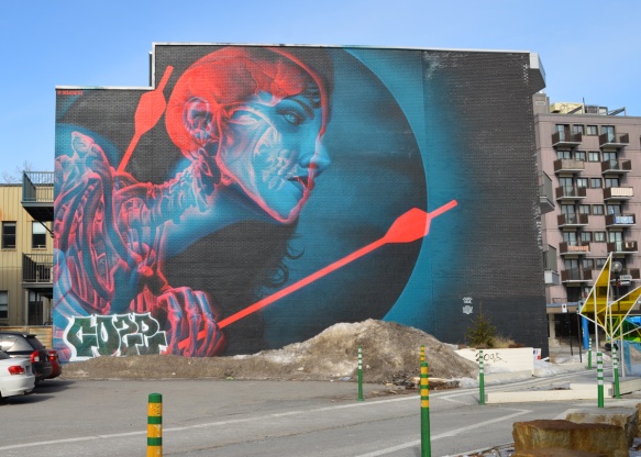large mural, red and blue, of a woman showing skeleton and brain, as well as body pierced by two red arrows, designed to be viewed with 3 D galsses, painted in Montreal by insane51 