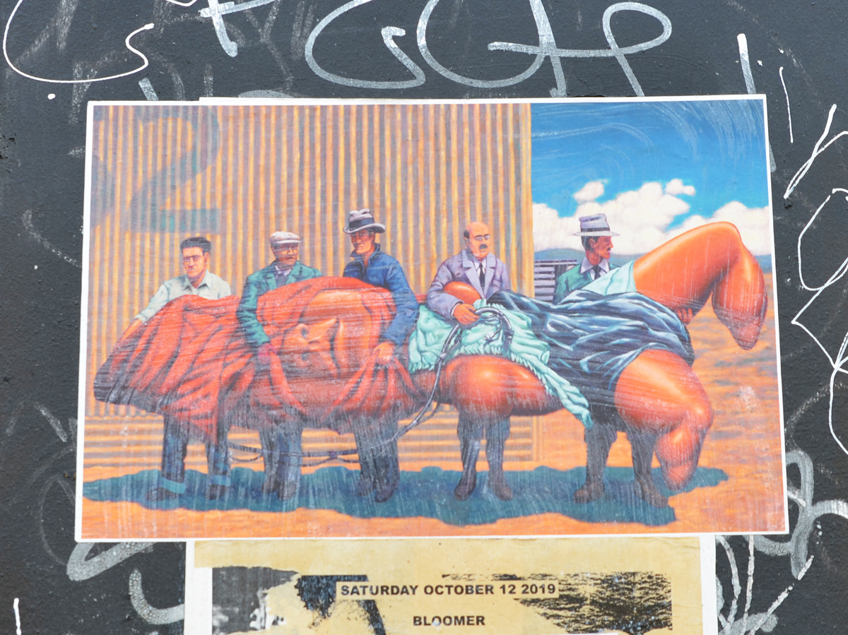 a street art poster on a wall, 5 men carrying something orange 