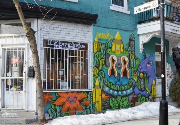 bookstore on a corner in Montreal, white window frame with bars on window, a mural by waxhead beside the window 