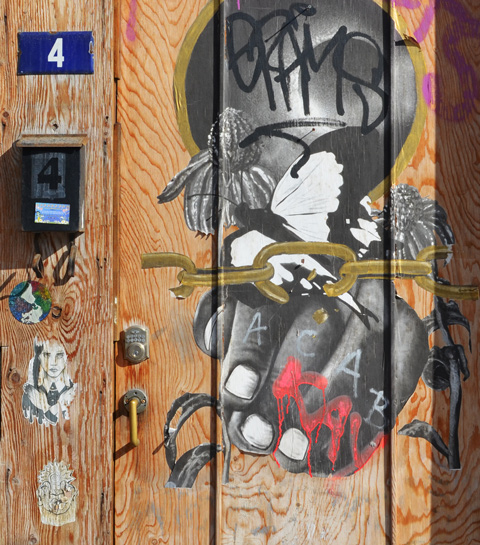 wood door with blue number 4 and 4 on a mailbox, with pasteups on the door too 
