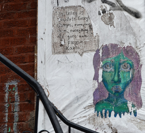 a green face with purple hair paste up beside a paper with words on it about Frida Kahlo
