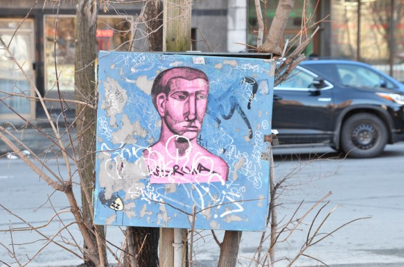 a paste up of a pink man's head and torso on a blue metal box, short hair, middle aged man