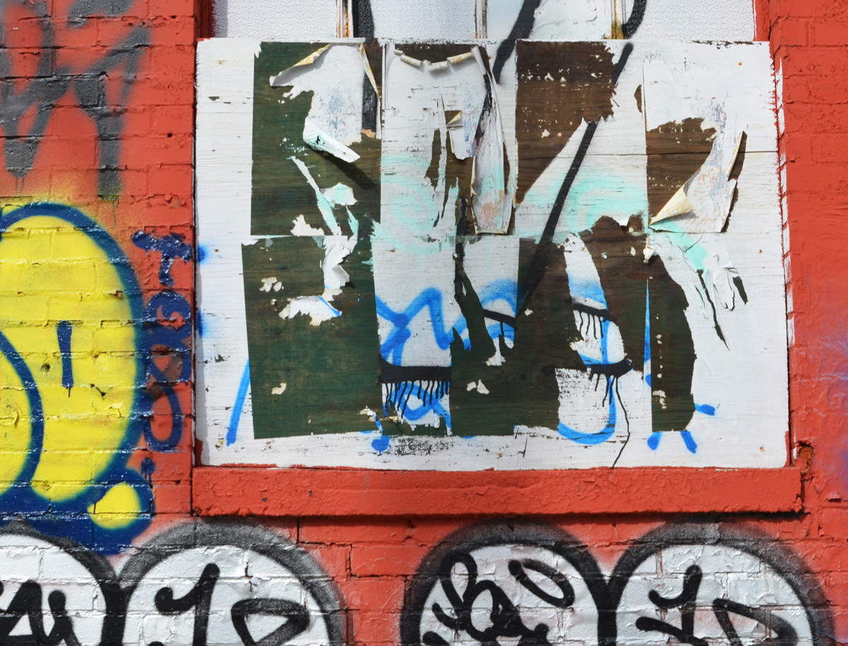 old posters and tags graffiti on a wall 