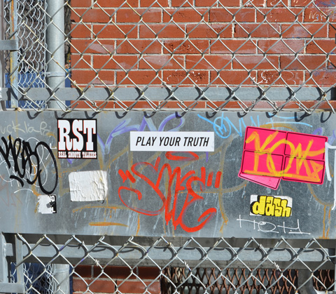 stickers on a metal gate, including one with the words play your truth 