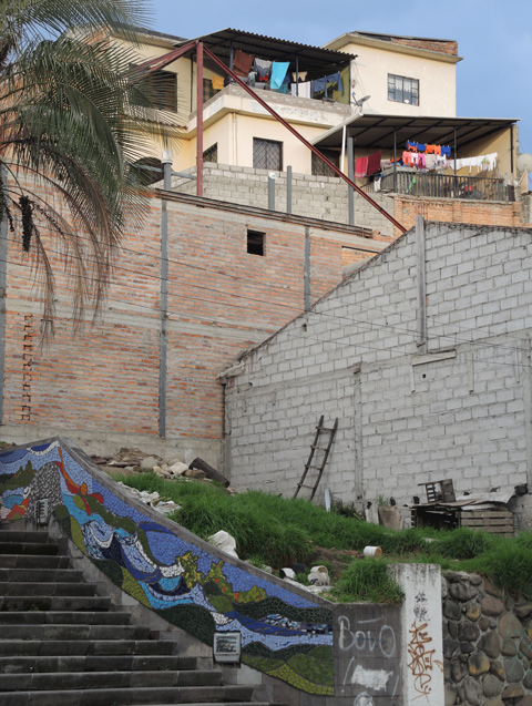 city houses on a hill with stairs below, mosaics on the wall 