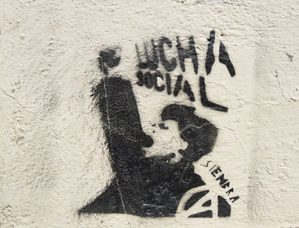 graffiti stencil in black of a man with fist upraised and open mouth, words lucha social